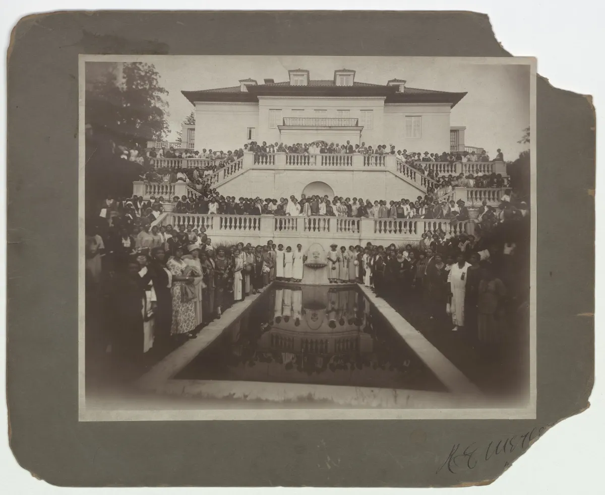 Black-and-white group photograph of dozens of Madam C.J. Walker's hair-care agents posed at Villa Lewaro, Walker's estate in Irvington-on-Hudson, New York, c. 1924. Rows of women in formal attire stand and sit on the steps in front of the Villa's columned portico.